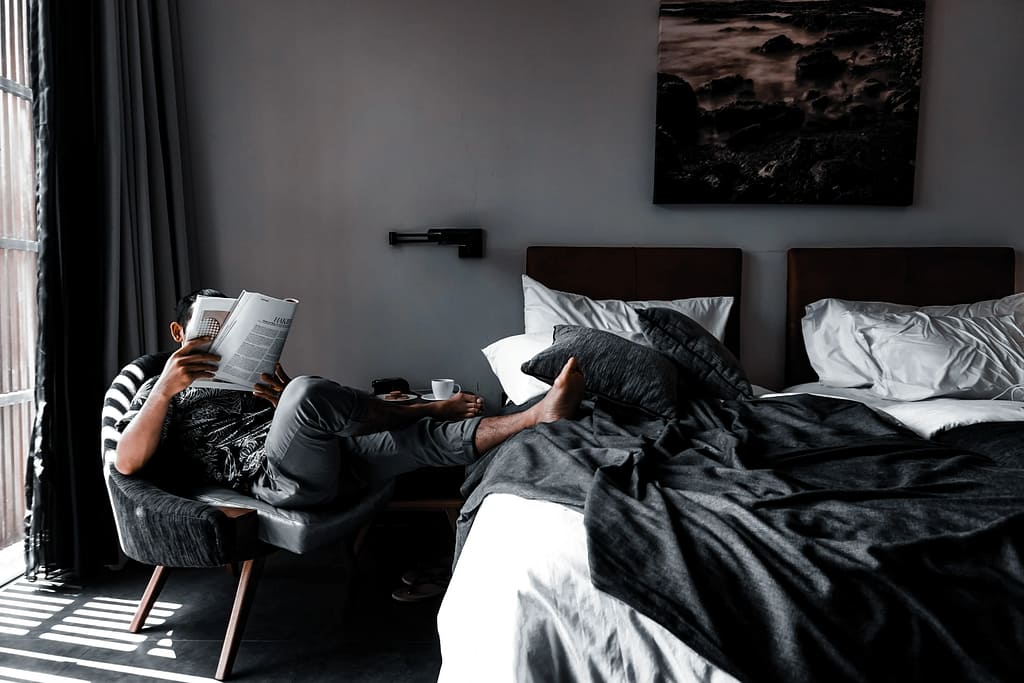 Man reading in bedroom, face hidden